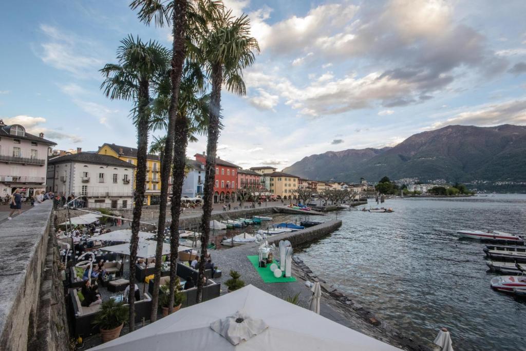 uitzicht op een rivier met palmbomen en gebouwen bij Seven Apartments in Ascona