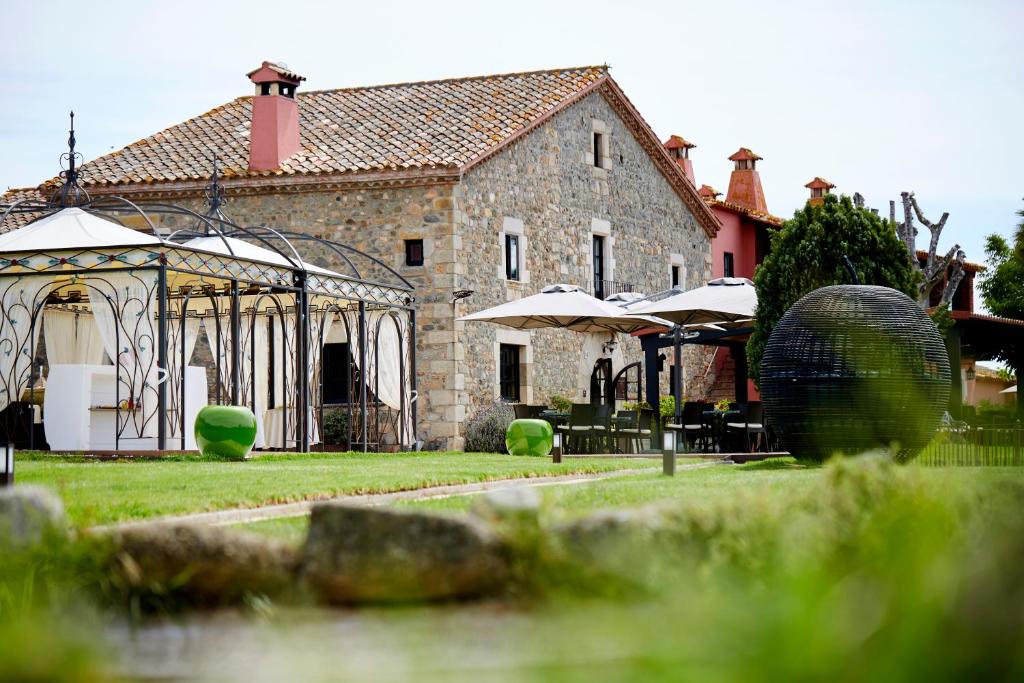 un edificio de piedra con cenador en un patio en Mas Tapiolas, en Santa Cristina d'Aro