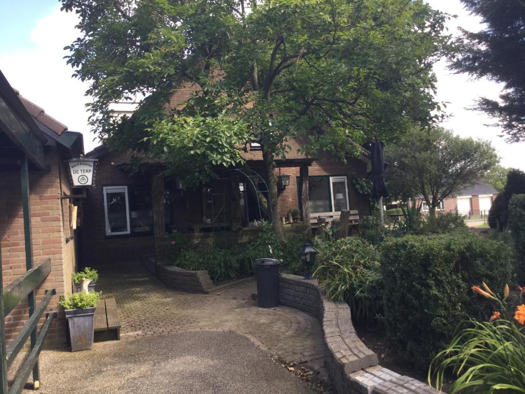una casa con un árbol delante de ella en De Terp, en Hernen