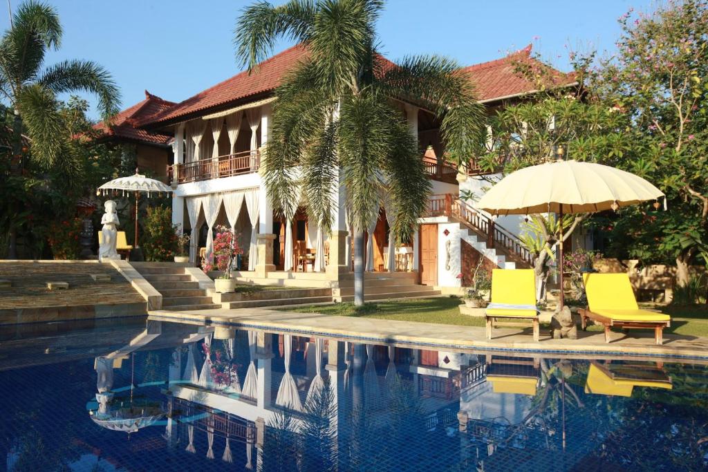 a house with a pool and two chairs and an umbrella at Villa Jakaranda and Villa Marakuya in Lovina