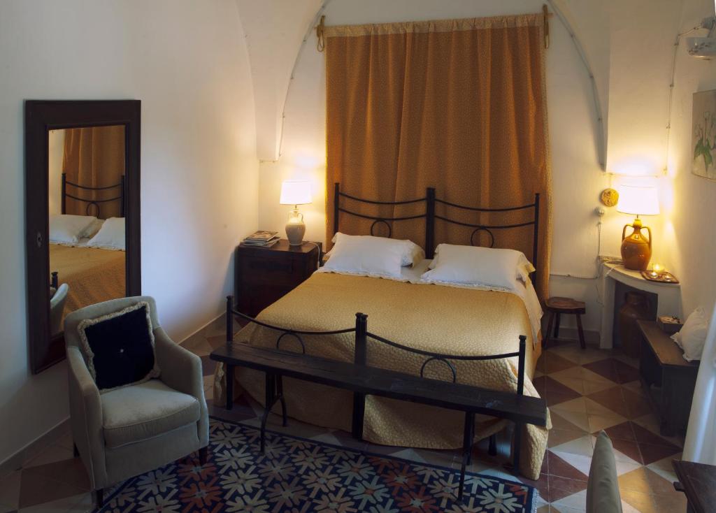 a bedroom with a bed and a chair and a mirror at Masseria Il Frantoio in Ostuni