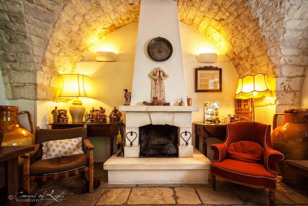 a living room with a fireplace and two chairs at Masseria Il Frantoio in Ostuni