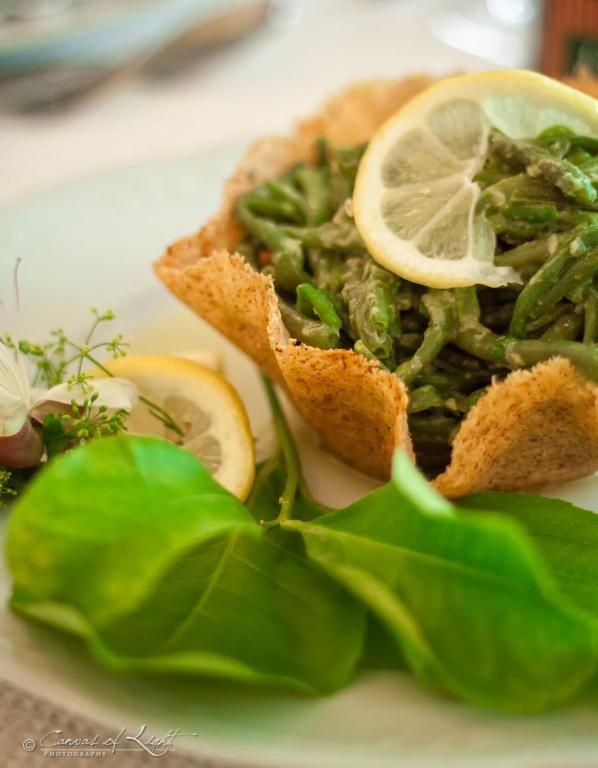 a plate with a sandwich with greens and lemon slices at Masseria Il Frantoio in Ostuni