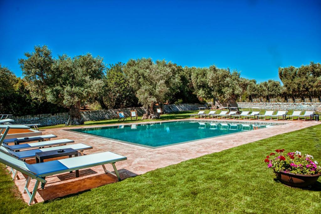 a swimming pool with lounge chairs in a yard at Masseria Il Frantoio in Ostuni
