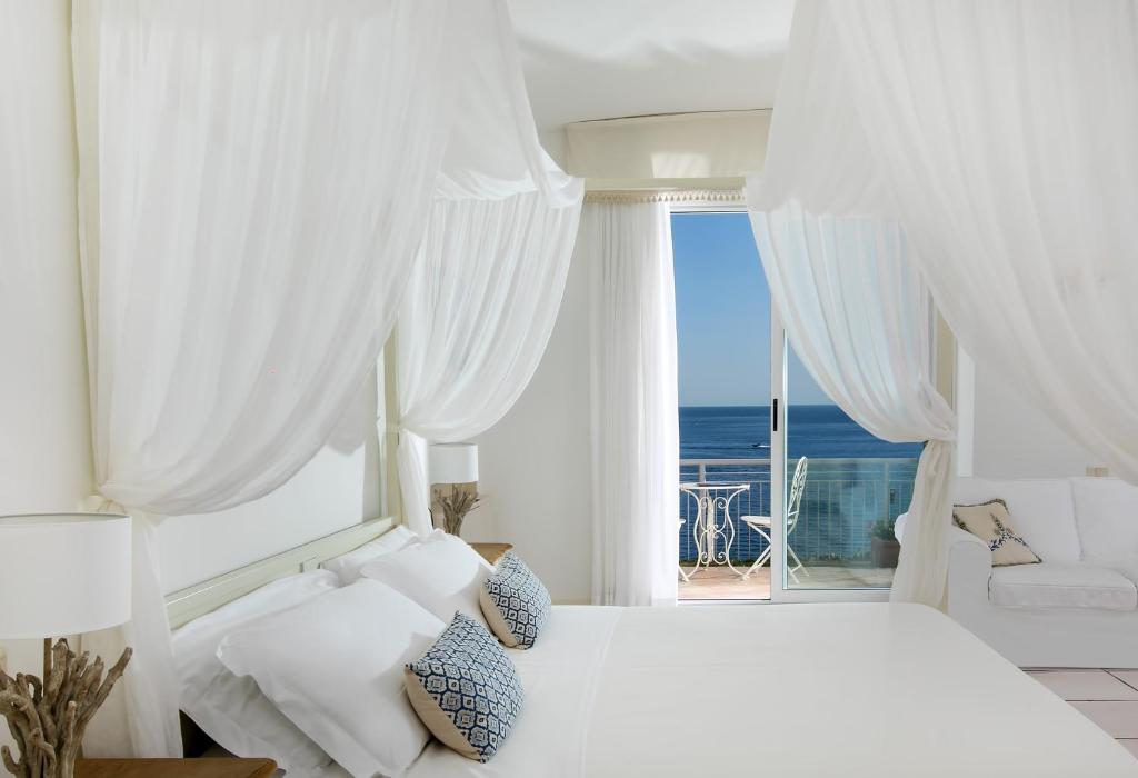 a white bedroom with a bed and a large window at Hotel Club Due Torri in Maiori
