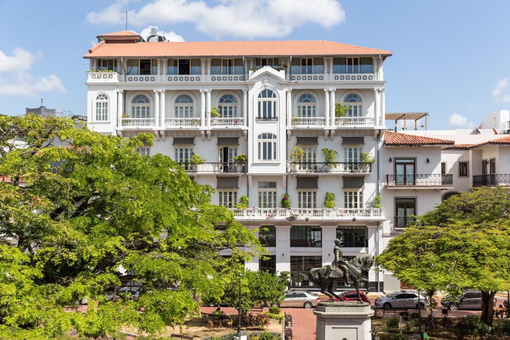 un grand bâtiment blanc avec des arbres devant lui dans l'établissement American Trade Hotel, à Panama City