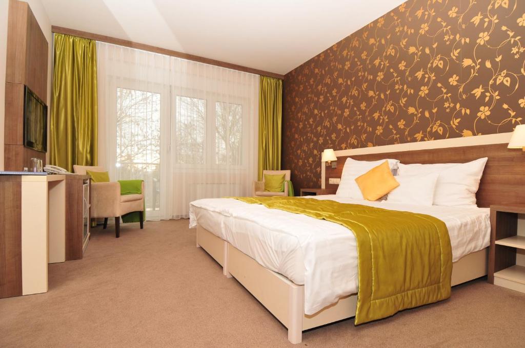 ドムボーバールにあるHotel Európa Gunarasのベッドルーム1室(大型ベッド1台、黄色い毛布付)