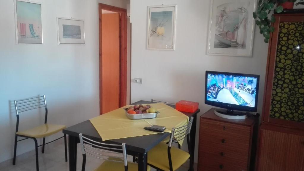 una sala da pranzo con tavolo e TV di Appartamento Monticello Vista Mare a Scalea