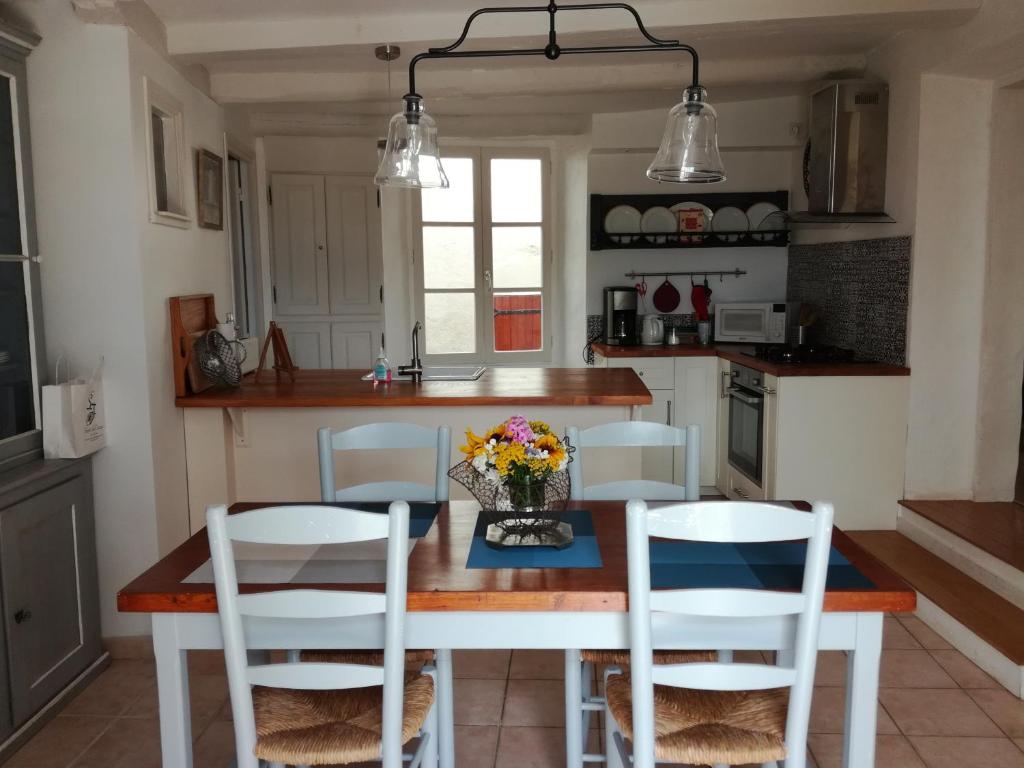 a kitchen with a table with chairs and flowers on it at Gîte du Besset in Pradelles