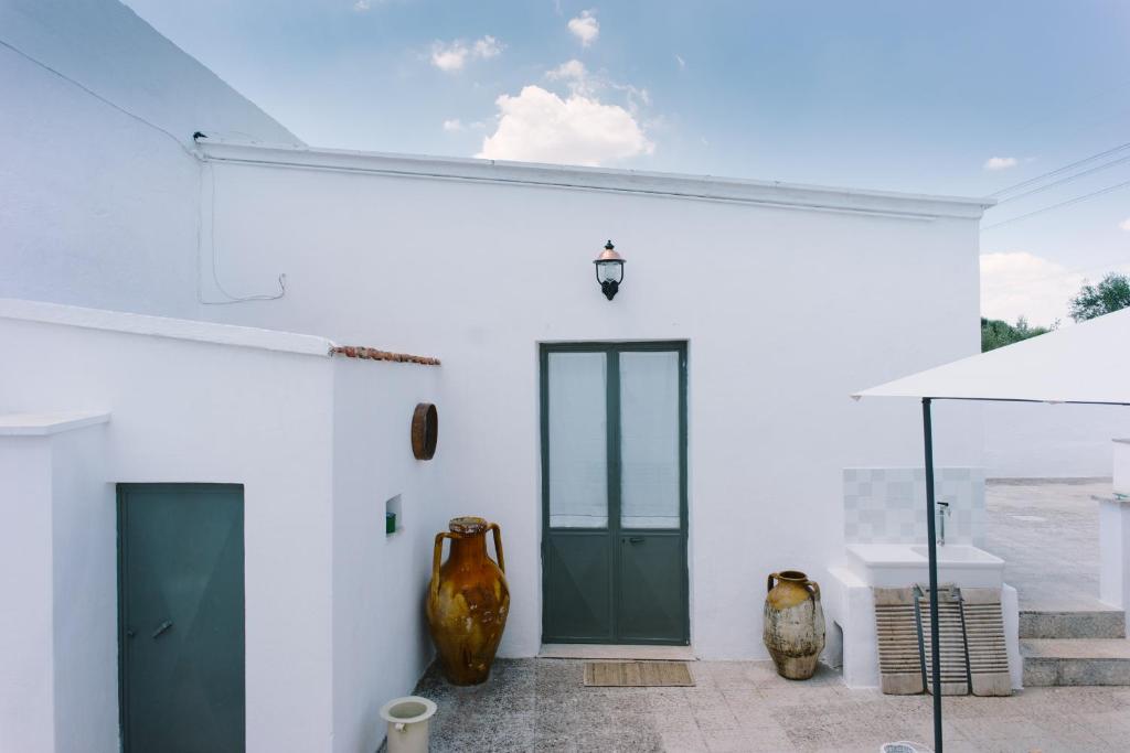 un edificio blanco con una puerta verde y jarrones en Masseria Cervellera, en Ceglie Messapica