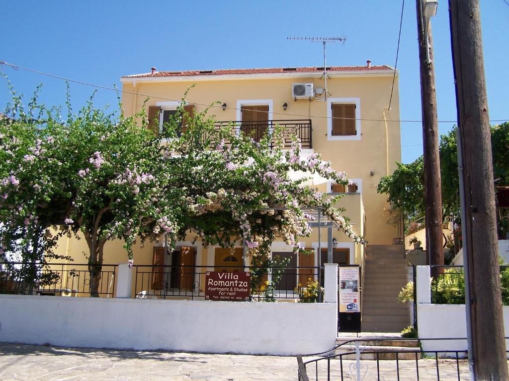 a yellow building with flowering trees in front of it at Villa Romantza in Fiskardo