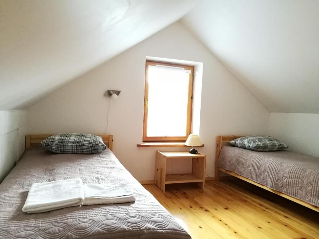 een slaapkamer op zolder met 2 bedden en een raam bij Svečių namelis in Druskininkai