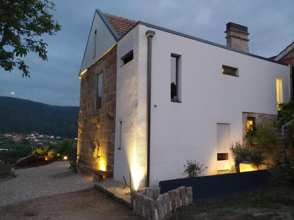 Una casa blanca con luces en el costado. en A casa dos Parladoiros en Mos