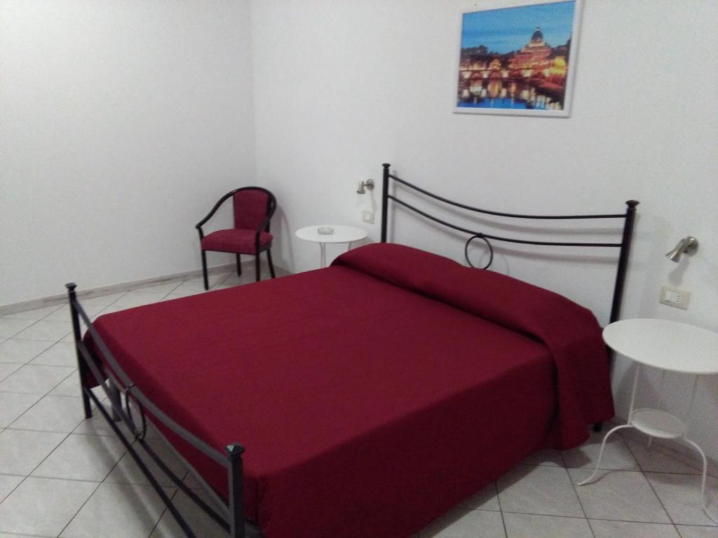 - une chambre avec un lit rouge et une chaise rouge dans l'établissement Caltagirone Casa Serena, à Caltagirone