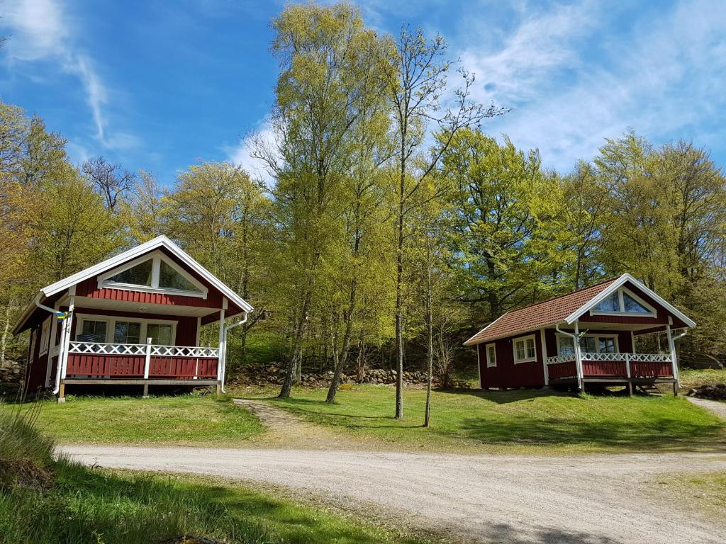 duas casas rústicas numa estrada de terra no bosque em Svalemåla Stugby em Bräkne-Hoby