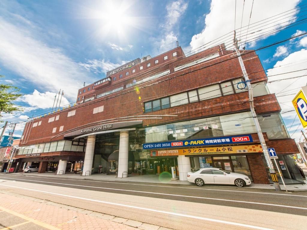 um edifício com um carro estacionado em frente em APA Hotel Komatsu Grand em Komatsu