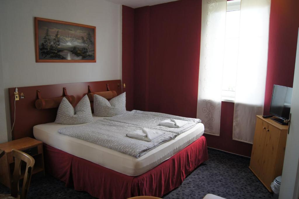 a bedroom with a bed with a red wall at Hotel Draschwitz in Draschwitz