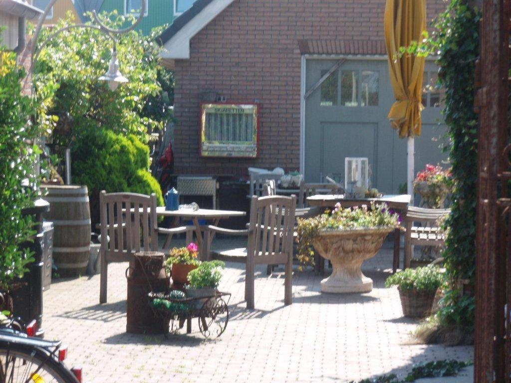a patio with a table and chairs and a table with flowers at Logement Brocante in De Koog