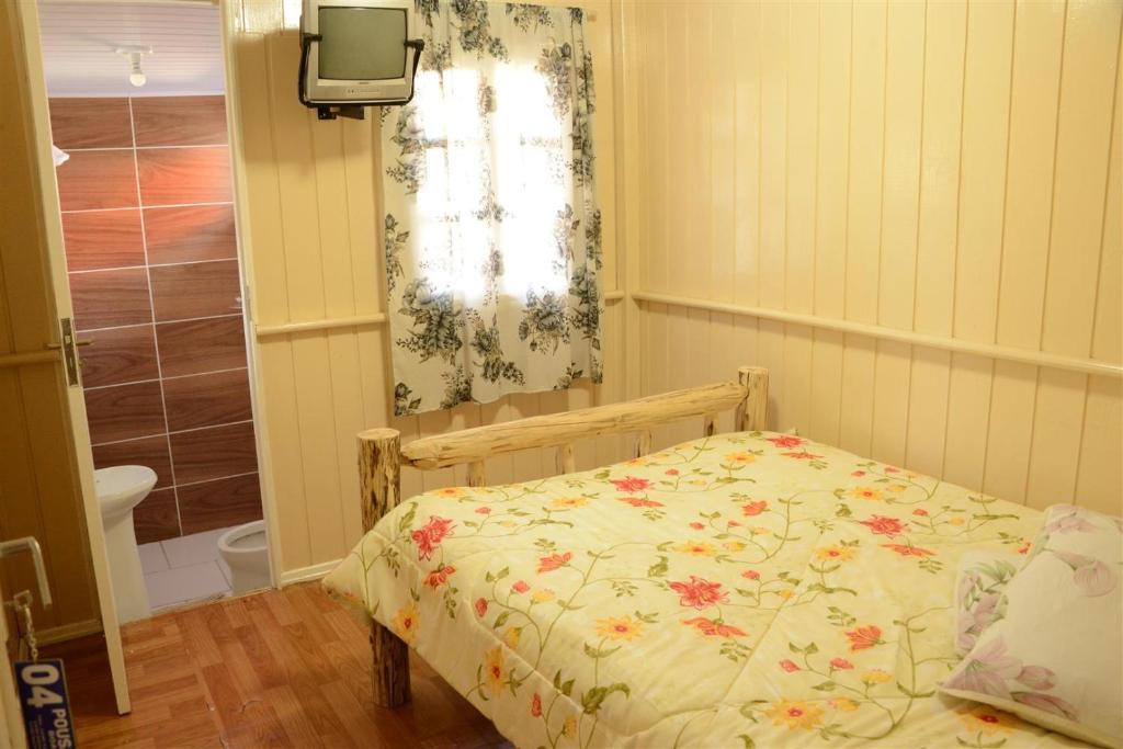 a bedroom with a bed with a floral bedspread at Pousada Boa Vista in São Joaquim