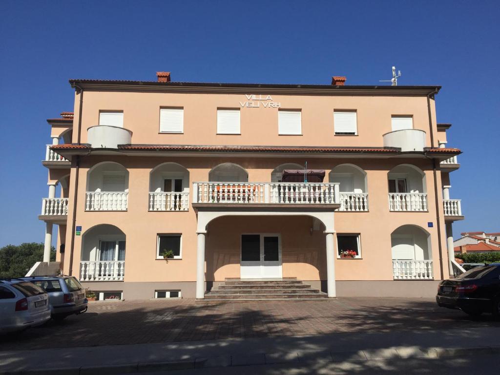 a large building with balconies and stairs in a parking lot at Villa Veli Vrh in Pula