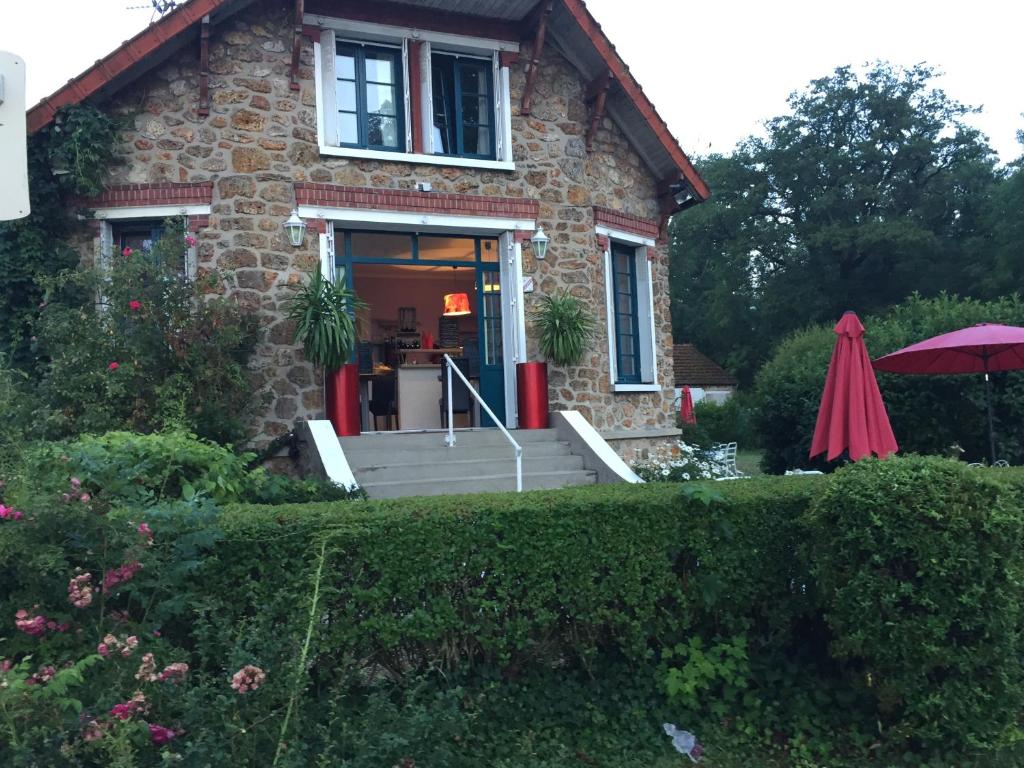 uma casa de tijolos com um alpendre em frente em Le Chant Des Oiseaux em Magny-les-Hameaux