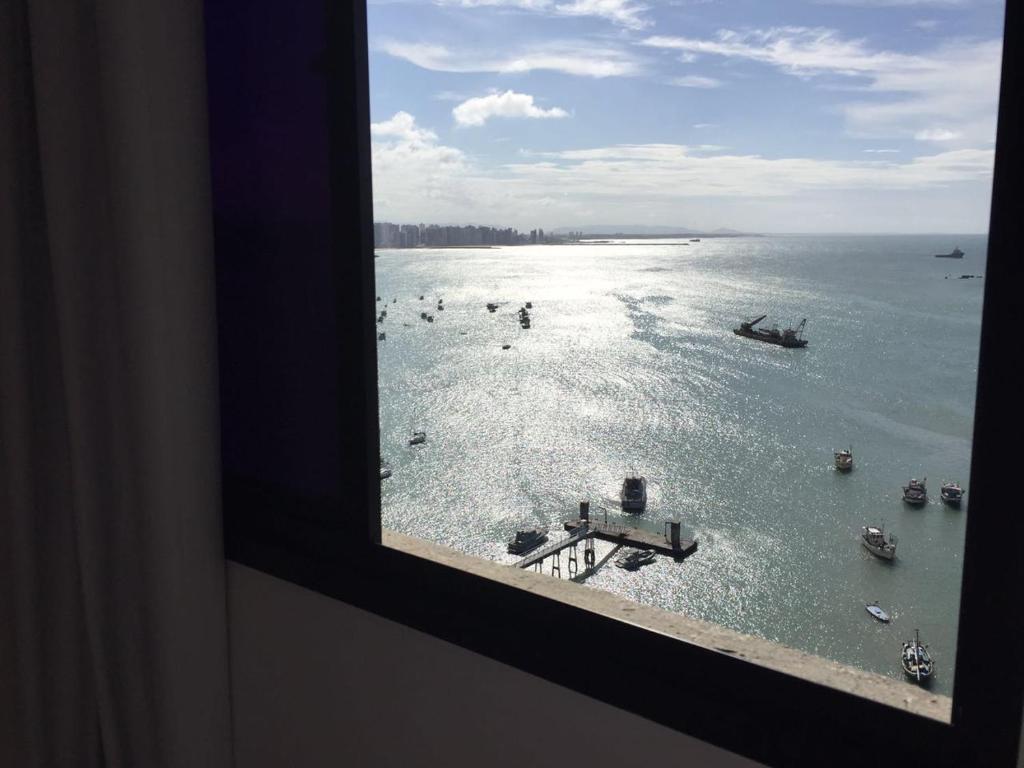 una ventana con vistas a un cuerpo de agua con barcos en Apart Porto Jangada Suíte Vista Mar, en Fortaleza
