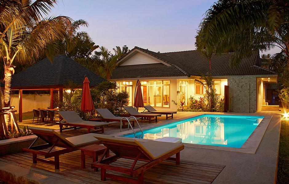 a swimming pool with lounge chairs and a house at Villa Raeya in Ao Nang Beach