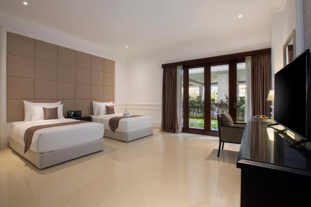 a hotel room with two beds and a television at Grand Palace Hotel Sanur - Bali in Sanur