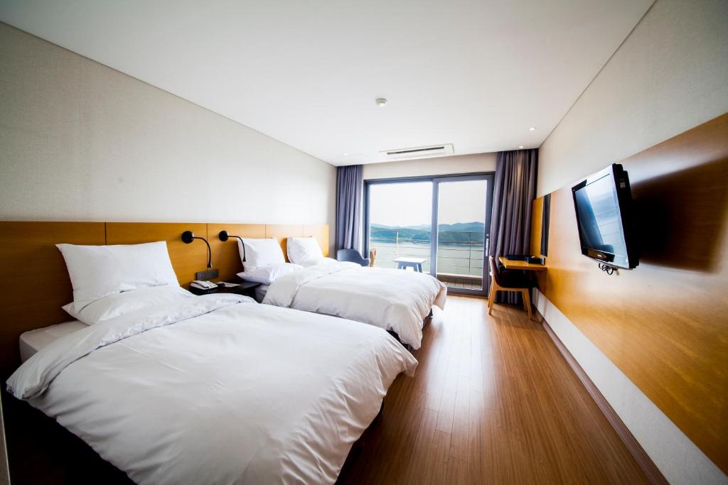 a hotel room with three beds and a television at Asia Lakeside Hotel in Jinju