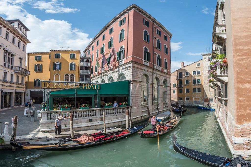 two gondolas in a canal in a city at Hotel Bonvecchiati in Venice