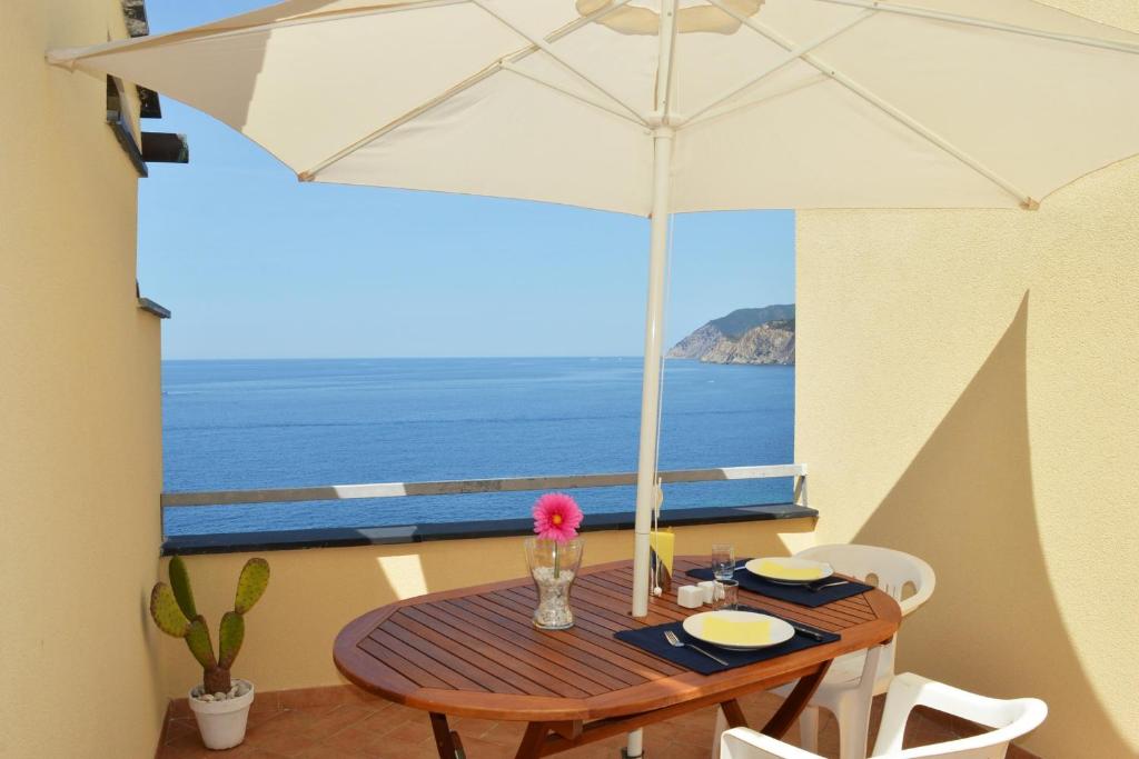 a table with an umbrella on a balcony with the ocean at House Grecale in Moneglia