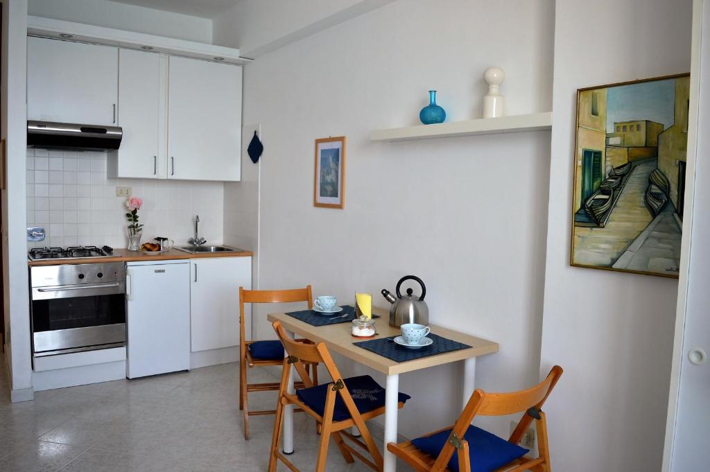 una cucina con tavolo e sedie e una cucina con armadietti bianchi di House Libeccio by Holiday World a Moneglia