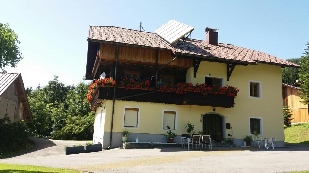 a house with a balcony with red flowers on it at idyllischer Landhof Nähe Millstättersee in Fresach