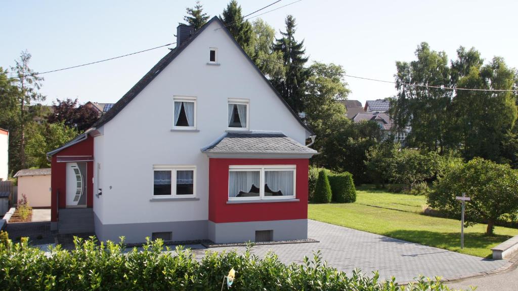 una casa blanca y roja con techo de gambrel en Ferienhaus am Flaumbach, en Blankenrath