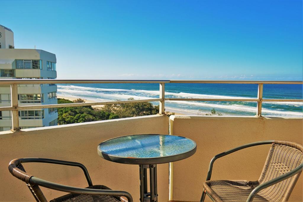 una mesa y 2 sillas en un balcón con vistas a la playa en Equinox Resort, en Gold Coast