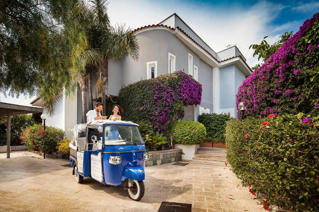 a man and a woman riding a small car in front of a house at Sorriso Thermae Resort & Spa in Ischia