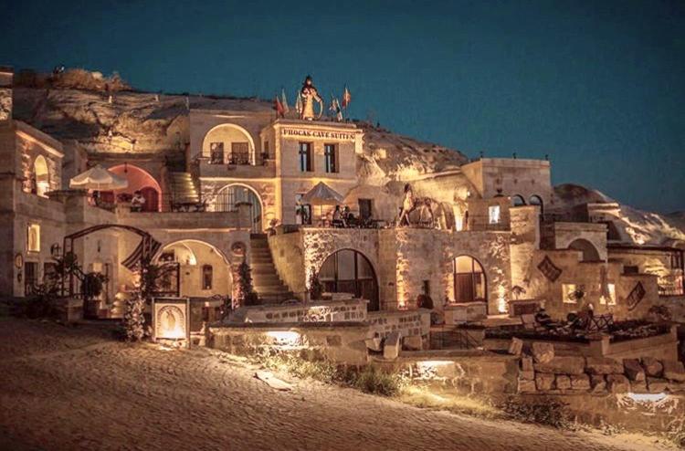 a large building on top of a mountain at night at Phocas Cave Suites in Göreme