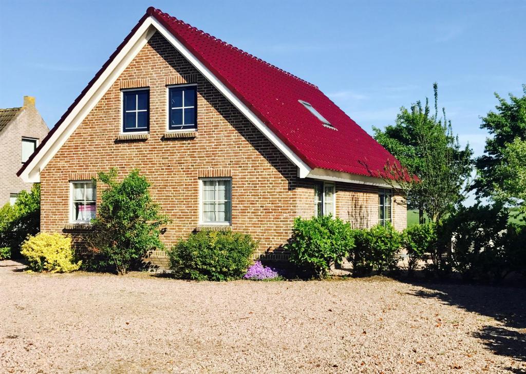 a brick house with a red roof at Vakantiehuis Tzummarum in Tzummarum
