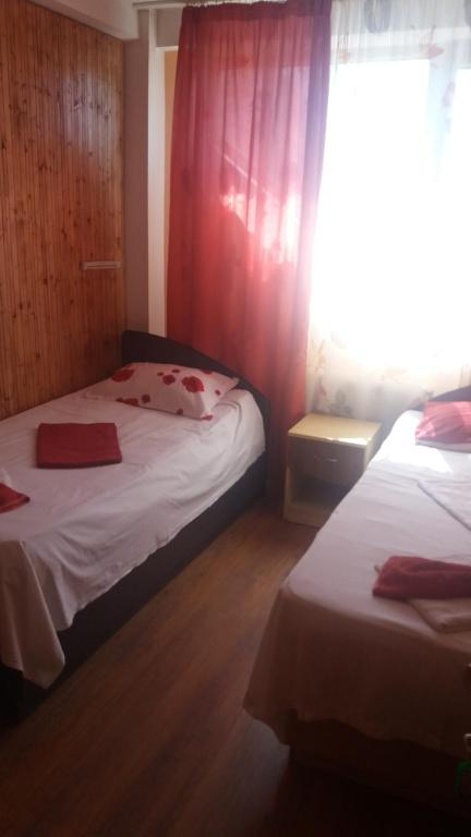 トゥルチャにあるPensiunea Nicol Tulceaのベッドルーム1室(ベッド2台付)、赤いカーテン付きの窓が備わります。