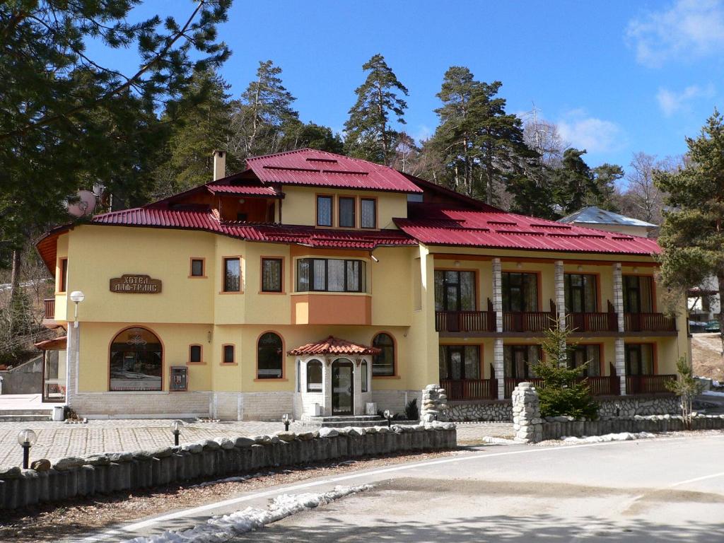 uma grande casa amarela com telhado vermelho em Daf Trans Hotel em Peshtera