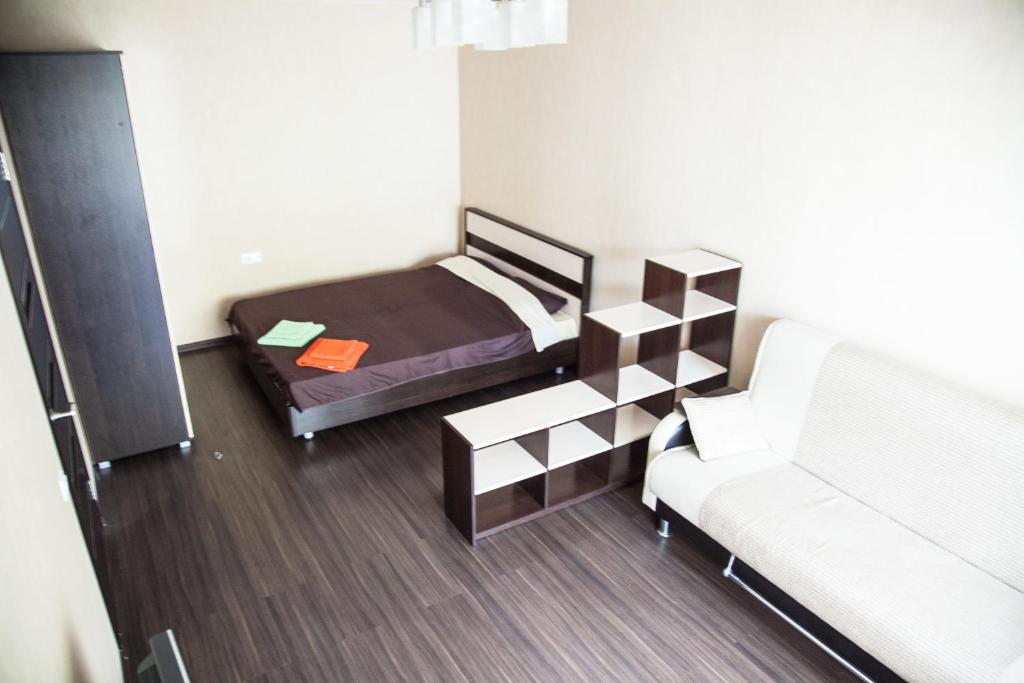 トムスクにあるАпартаменты Учебная 7のベッド1台とソファが備わる小さな客室です。