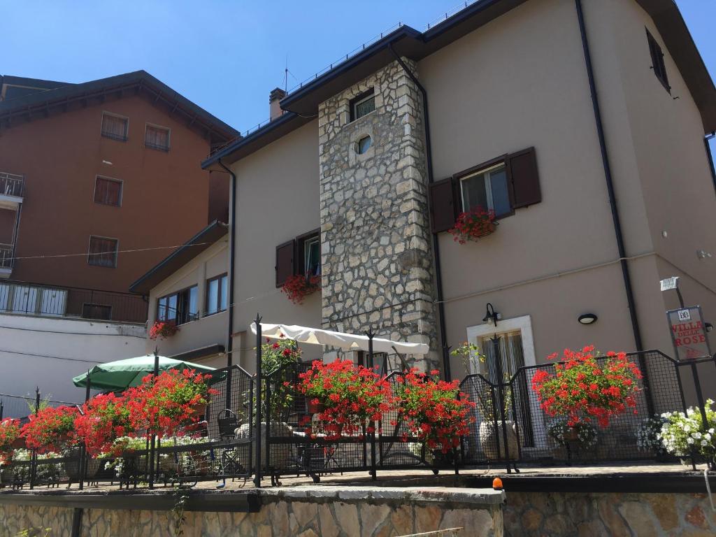 a building with red flowers in front of it at B&B Villa Delle Rose in Roccaraso