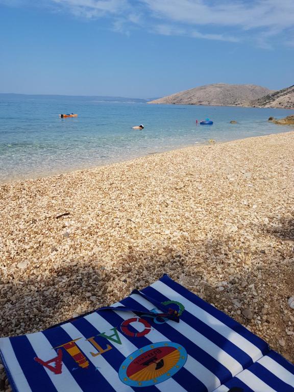 a towel on the beach with people in the water at Apartment La-Vi in Stara Baška