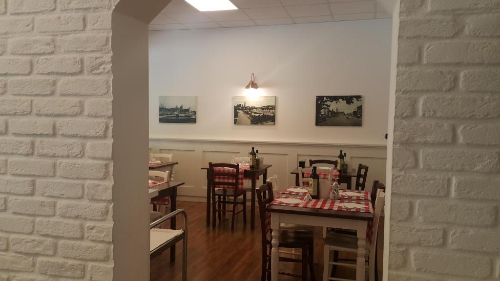 a dining room with tables and chairs and a white brick wall at Albergo Pizzeria Sole in San Giovanni Lupatoto