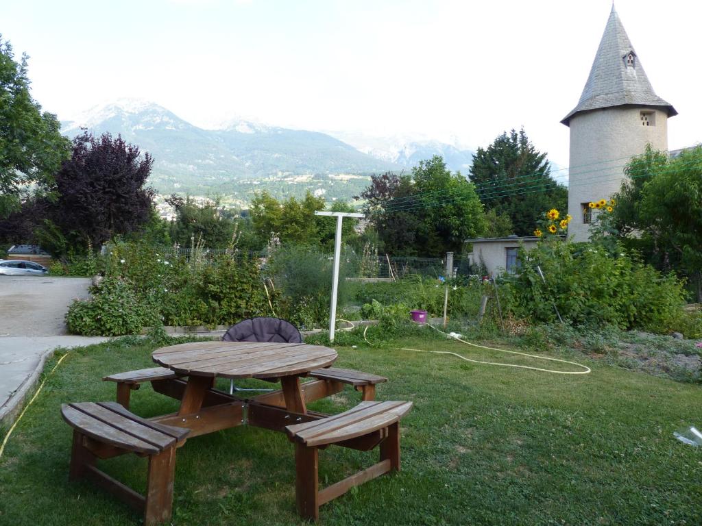 a picnic table and two benches in the grass at Appartement L'Orel in Embrun