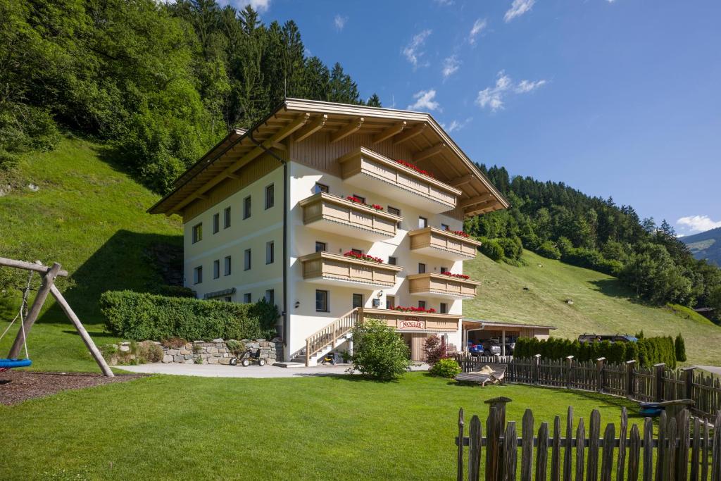 un grande edificio su una collina con parco giochi di Ferienhof Nogler a Zellberg