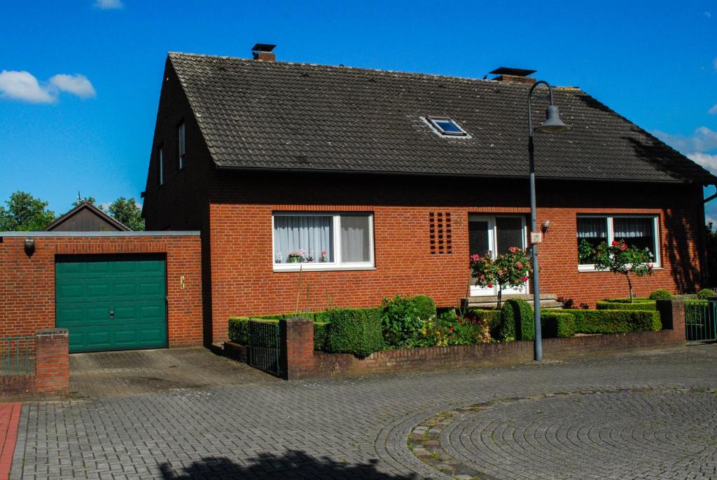een rood bakstenen huis met een groene garage bij Ferienwohnung Wolf in Greven