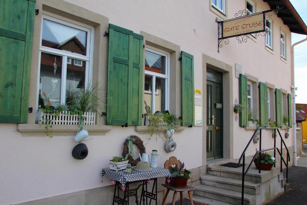 a building with green shutters and a table in front of it at Pension Gute Stube in Sulzfeld (im Grabfeld)