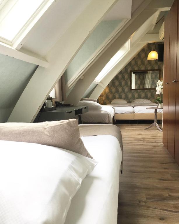 a row of beds in a room with an attic at Hotel Johannes Vermeer Delft in Delft