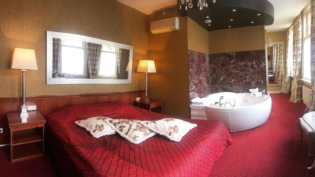 a bedroom with a bed and a bathtub and a tub at Hotel Johannes Vermeer Delft in Delft